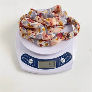 Detail shot of lightweight floral satin headscarf weighing 9.3g on white scale