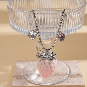 Detailed view of pink strawberry pendant with silver bead chain and zircons on marble