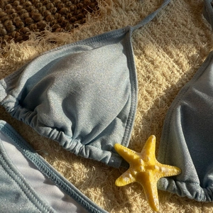Macro detail of sparkly light blue bikini fabric with shimmering metallic golden silk texture