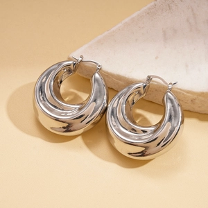 Macro shot of silver crinkled U-shaped hoop earrings on a beige marble stone