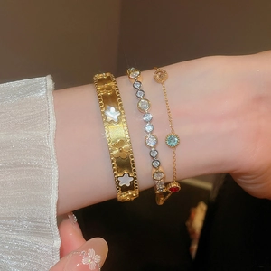 Close-up of stacked gold floral bangle and colorful gemstone bracelets on model wrist
