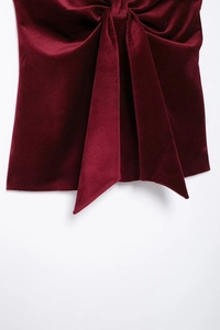 Gros plan sur un tissu en velours rouge luxueux avec un grand nœud décoratif