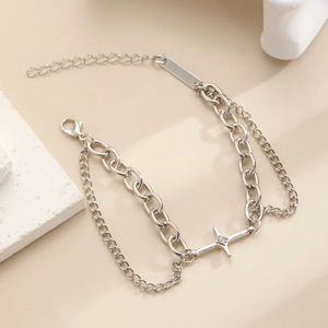 Detail of silver double-layer chain bracelet featuring a four-point star charm with crystal