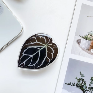 Macro detail of leaf-shaped phone grip with realistic green plant vein pattern on white desk