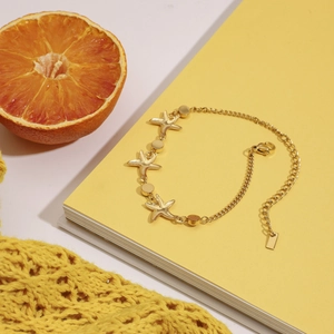 Detailed shot of golden starfish bracelet with colorful zircon on a yellow book background