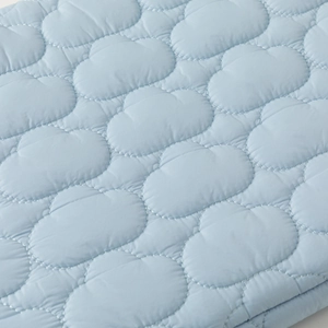 Close-up of light blue cloud-shaped quilting embroidery and soft fabric texture
