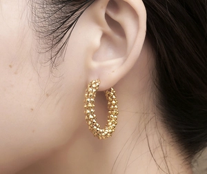 Close-up of golden textured hoop earrings with retro popcorn grain finish on model