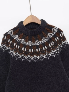 Dettaglio maglione grigio lavorato a maglia con motivo jacquard vintage su gruccia in legno