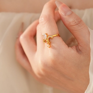 Close-up of golden fleur-de-lis ring with white zircons on index finger for vintage style