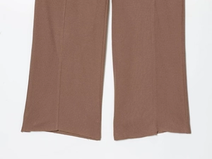 Detail of brown ribbed knit trousers hem showing natural raw edge texture and fine fabric