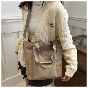 Detail of khaki nylon tote bag showing adjustable wide shoulder strap and dual handles