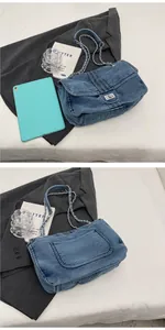 Detail of dark blue denim tote bag showing metal chain strap and large back pocket