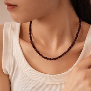 Close-up of deep red beaded clavicle necklace on model wearing a white top