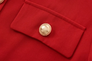 Detailed close-up of a red textured cropped jacket featuring a polished gold button