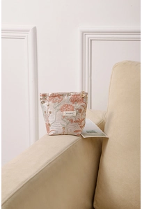 Close-up of beige fabric makeup bag with floral embroidery and floral zipper puller