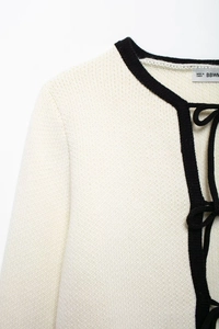 Détail d'un cardigan blanc en maille avec bordures noires et texture du tissu doux