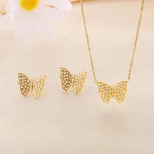 Elegant gold butterfly necklace and earrings set with tiny faux pearls on beige background