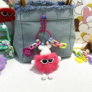 Porte-clés monstre en peluche rose avec lunettes de soleil accroché sur un sac en denim