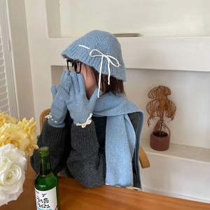 Detail shot of soft blue knitted scarf, hat and gloves set with white ribbon bow accents