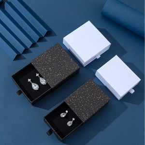 Dettaglio di portagioie a cassetto in oro nero e bianco con nastro e interni vellutati