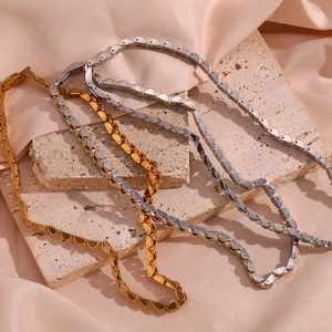 Detail of 18K gold and silver 6mm watch-strap chain necklaces on silk and stone