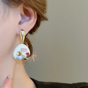 Nahaufnahme der Vintage-Blumenohrringe mit Emaille-Blütenblättern am Ohr