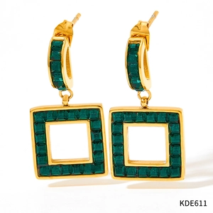 Gros plan de boucles d'oreilles carrées dorées avec pierres précieuses vertes serties