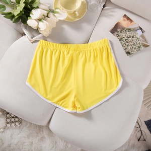 Flat lay of yellow athletic shorts with white trim on a white decorative surface
