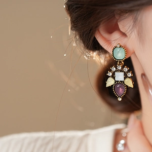 Close-up of vintage drop earrings with colorful crystals on model with soft lighting