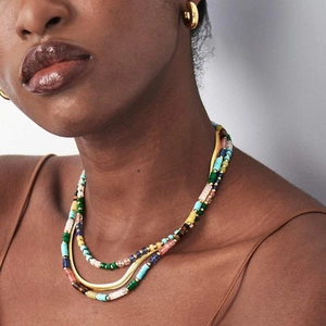 Detail of layered natural stone beaded necklace with a golden snake chain on a model