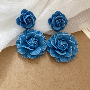 Detailed view of blue denim fabric flower drop earrings with frayed edge rose petals