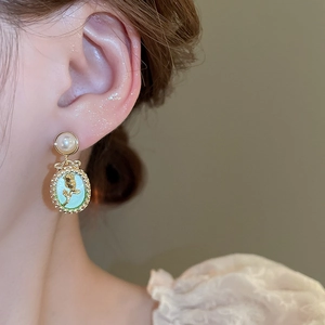 Macro view of French vintage tulip flower earrings with mint green oval pendant and pearl