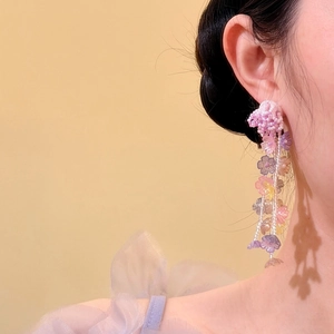 Detailed view of colorful beaded floral tassel earrings on ear, vacation style