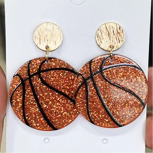 Close-up of sparkling orange basketball drop earrings with golden metallic studs