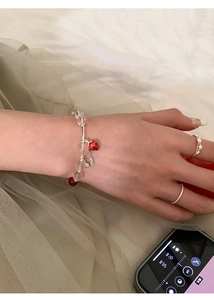 Detail of strawberry charm bracelet with glass beads and silver flower ring set