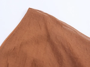 Detail of caramel brown dress fabric showing pleated texture and neat stitching