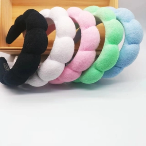 Close-up of five colorful plush sponge headbands neatly arranged on a wooden storage box