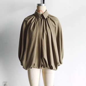 Detail of khaki pleated oversized puff jacket with turn-down collar and bronze zipper