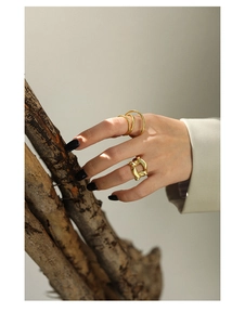 Close-up of minimalist gold hollow geometric rings worn on fingers with wooden props