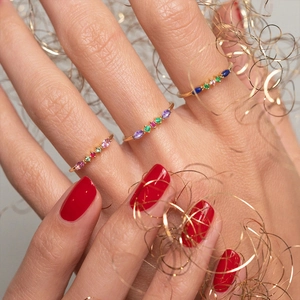 Macro shot of three thin gold bands with colorful cubic zirconia stones in marquise cuts