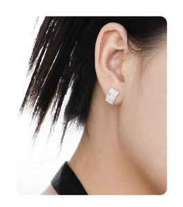 Close-up of S925 silver square earring with brushed texture and zircon on earlobe