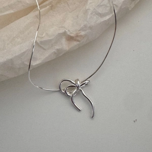 Minimalist 925 sterling silver bow pendant necklace with sleek snake chain on paper