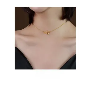 Close-up of minimalist gold geometric interlocking square pendant on a collarbone chain