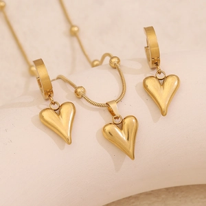 Macro shot of gold heart jewelry set with necklace and earrings on textured base