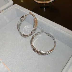 Detailed view of silver triple-layered interwoven hoop earrings in a gray jewelry box