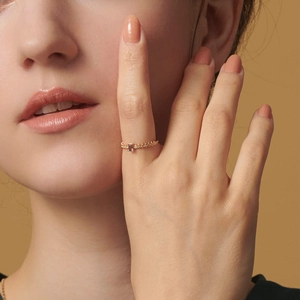 Detail of a vintage gold ring with pink gemstone and beaded band on a finger