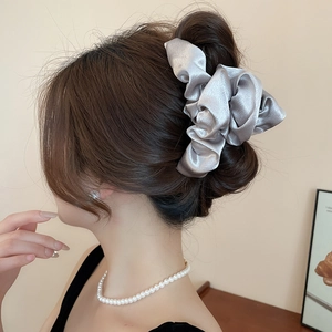 Elegant silver grey satin cloud scrunchie worn on a bun hairstyle with silk texture