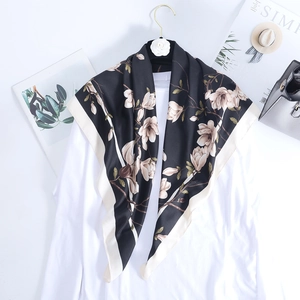 Close-up of a silk satin square scarf featuring white floral prints on a black background
