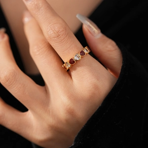 Close-up of vintage gold heart ring with red enamel and zircon stones on a hand