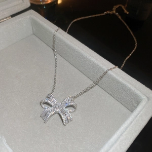 Detailed view of silver bow necklace pendant set with clear baguette and round zircons